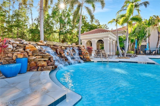 pool with a patio area, an outdoor structure, and a storage structure