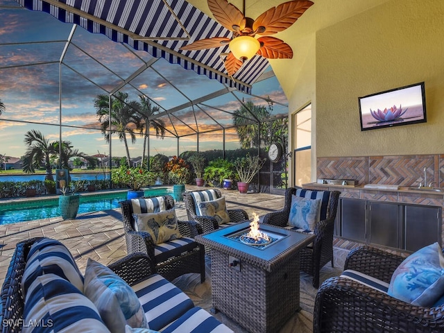 patio terrace at dusk with sink, an outdoor living space with a fire pit, and glass enclosure