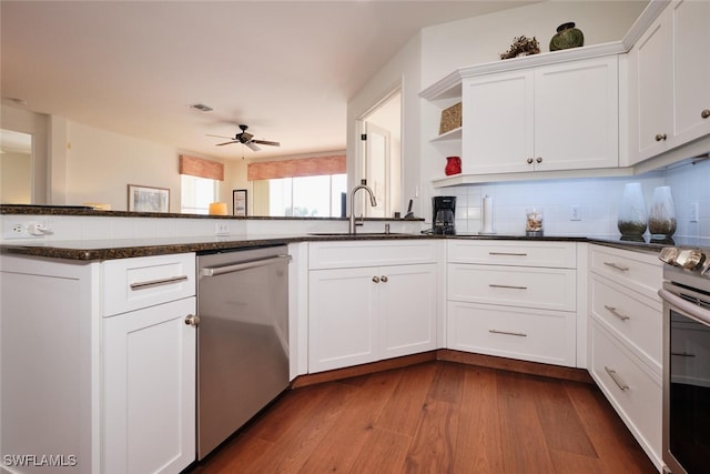 kitchen featuring sink, white cabinetry, appliances with stainless steel finishes, hardwood / wood-style floors, and decorative backsplash