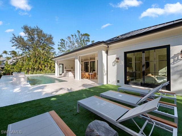 back of property featuring exterior bar, a patio area, and a lawn