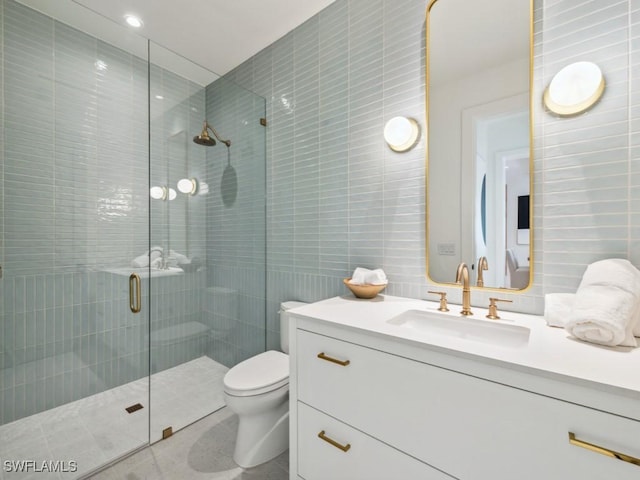 bathroom with tile walls, vanity, a shower with door, and toilet