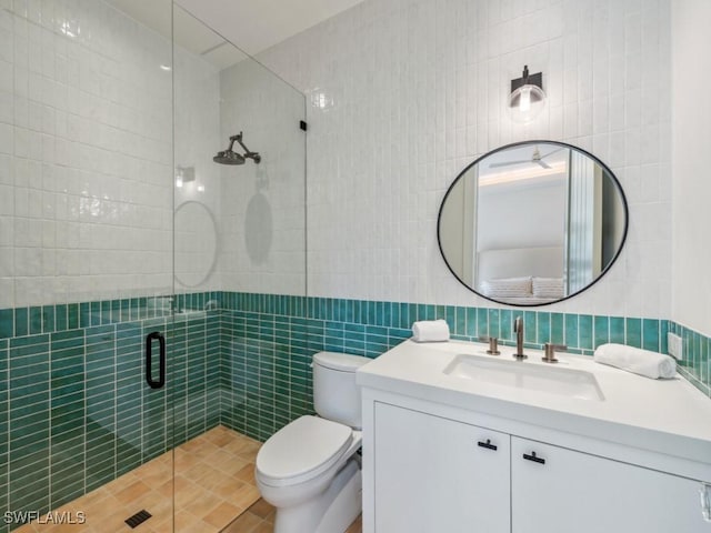 bathroom featuring tile walls, vanity, a shower with shower door, and toilet