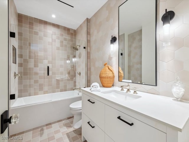 full bathroom featuring tile walls, vanity, tiled shower / bath combo, and toilet