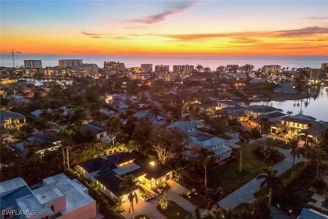 aerial view at dusk featuring a water view