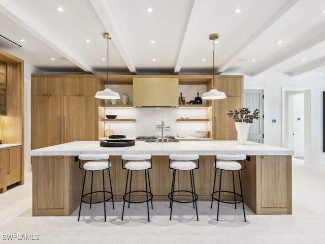 kitchen with sink, decorative light fixtures, and a large island with sink