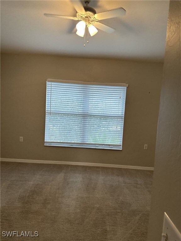 carpeted spare room featuring ceiling fan