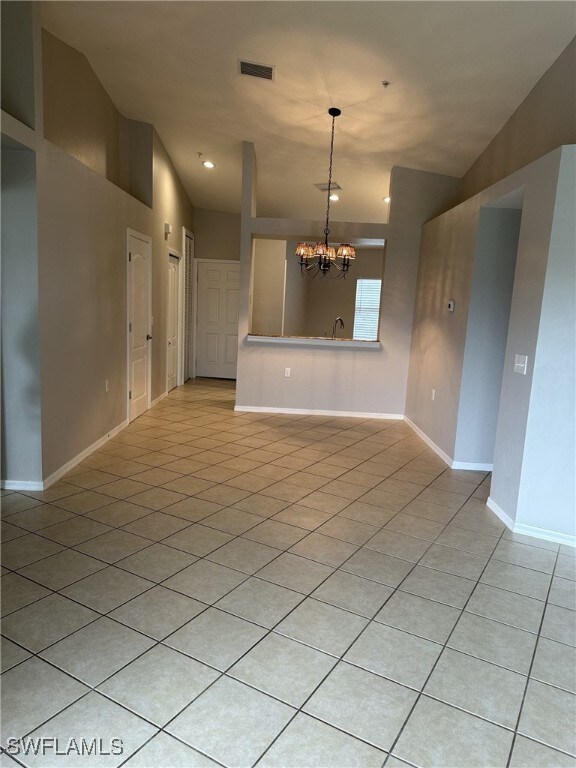 tiled empty room with sink and a chandelier