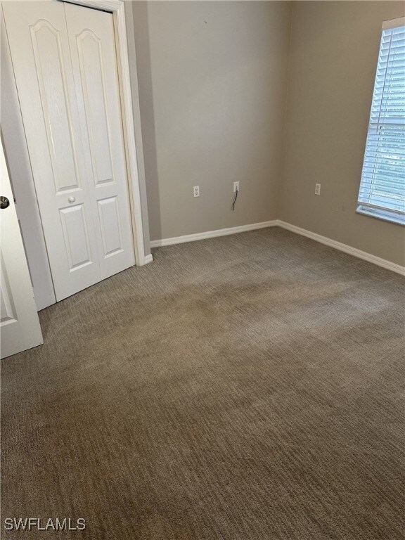 unfurnished bedroom with dark colored carpet