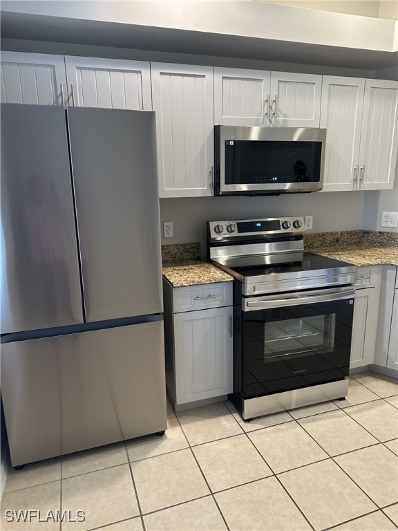 kitchen featuring appliances with stainless steel finishes, stone countertops, light tile patterned floors, and white cabinets