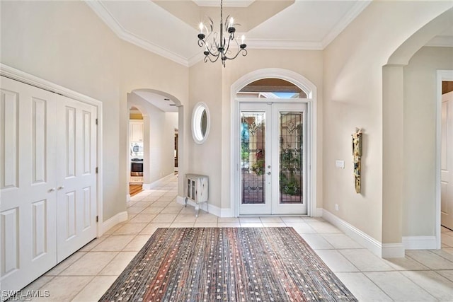 entryway with light tile patterned flooring, ornamental molding, a notable chandelier, and french doors