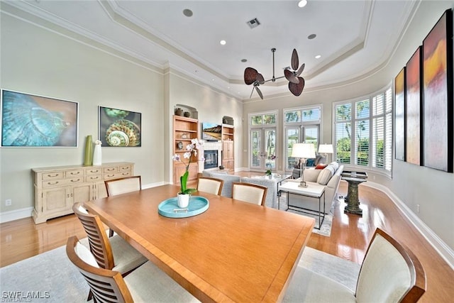 dining room featuring french doors, light hardwood / wood-style flooring, built in features, and a tray ceiling