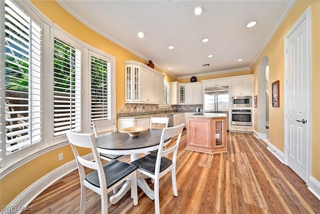 dining space featuring ornamental molding, sink, and light hardwood / wood-style floors