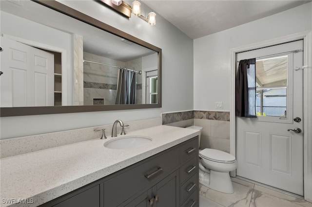 full bath featuring toilet, marble finish floor, curtained shower, vanity, and tile walls