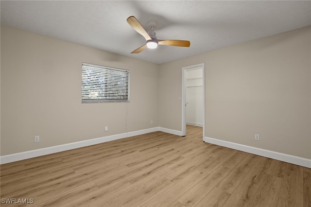 unfurnished room featuring baseboards, a textured ceiling, a ceiling fan, and light wood-style floors