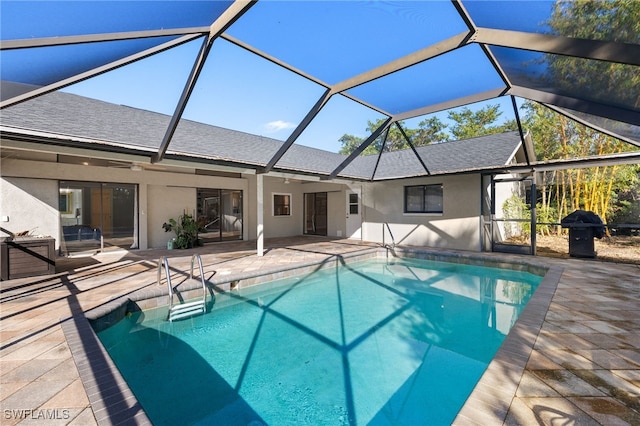 outdoor pool featuring glass enclosure and a patio