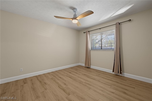 spare room with light wood-style floors, baseboards, and a textured ceiling