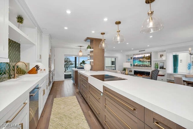 kitchen featuring sink, decorative light fixtures, stainless steel dishwasher, dark hardwood / wood-style flooring, and white cabinets