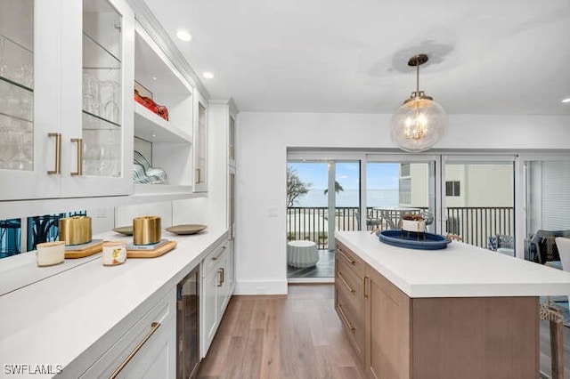 kitchen featuring white cabinetry, wine cooler, hanging light fixtures, and light hardwood / wood-style flooring