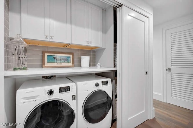 washroom featuring cabinets, wood-type flooring, and washer and dryer