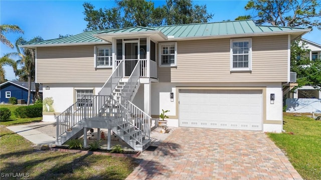 view of front facade featuring a front lawn, a garage, and a sunroom