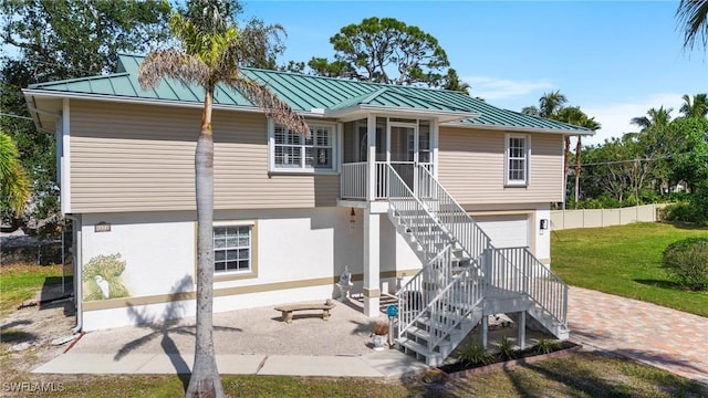 view of front of home featuring a garage, a patio, a sunroom, and a front lawn