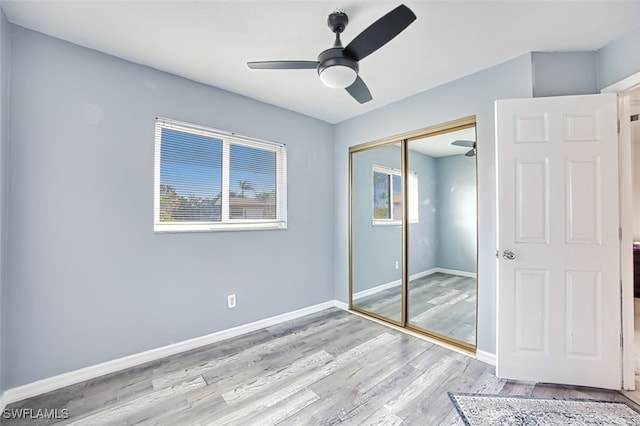 unfurnished bedroom featuring ceiling fan, light hardwood / wood-style floors, and a closet