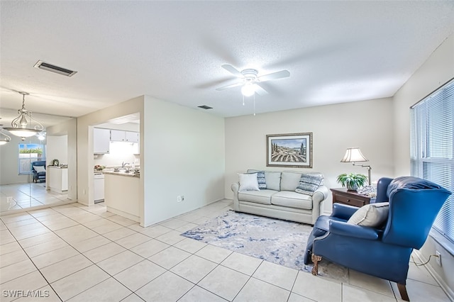 living room featuring ceiling fan, light tile patterned floors, and a textured ceiling