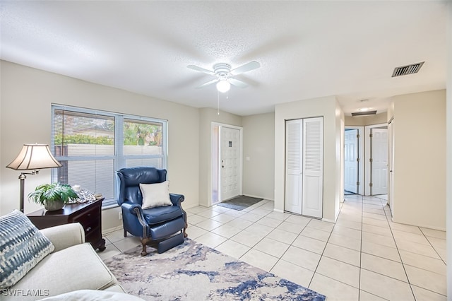 living room with ceiling fan, light tile patterned floors, and a textured ceiling