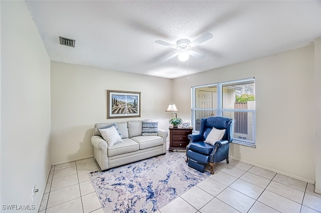 living room featuring ceiling fan, light tile patterned floors, and a textured ceiling