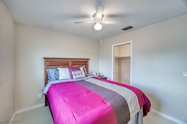 bedroom with a walk in closet, light colored carpet, ceiling fan, and a closet