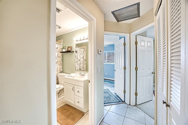 bathroom with tile patterned floors, toilet, crown molding, a textured ceiling, and vanity