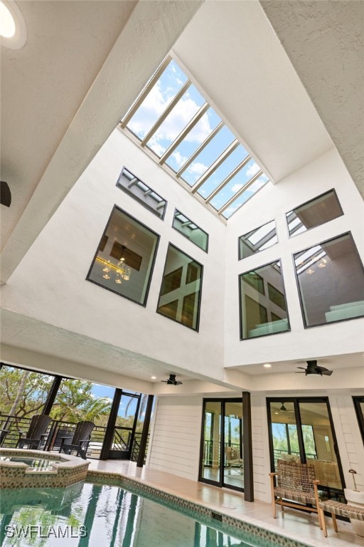 rear view of property with a patio area, ceiling fan, and a pool with hot tub