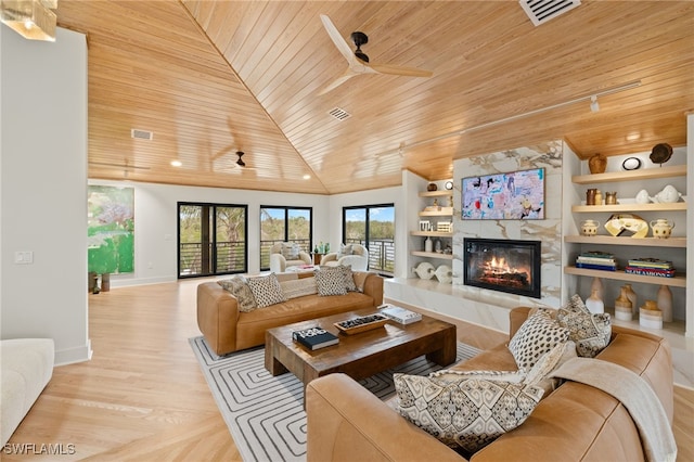 living room with lofted ceiling, a premium fireplace, ceiling fan, built in shelves, and wooden ceiling