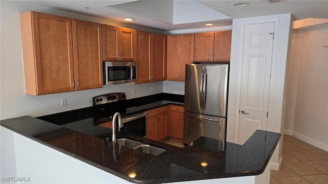 kitchen with sink, kitchen peninsula, appliances with stainless steel finishes, and dark stone countertops