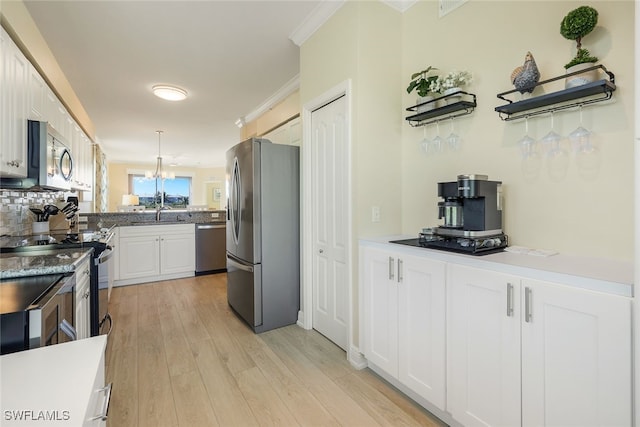 kitchen with white cabinetry, decorative light fixtures, light wood-type flooring, ornamental molding, and stainless steel appliances