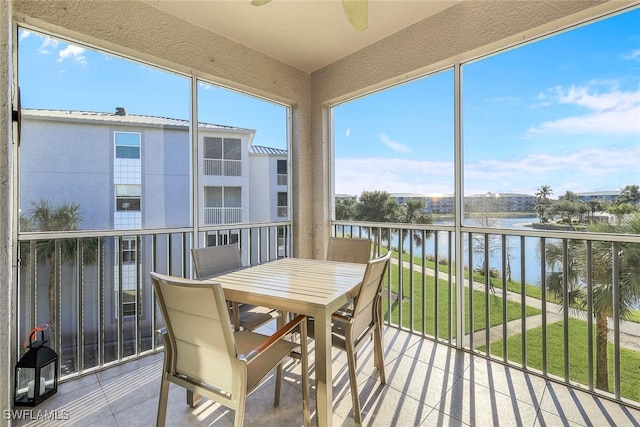 sunroom featuring a water view and ceiling fan