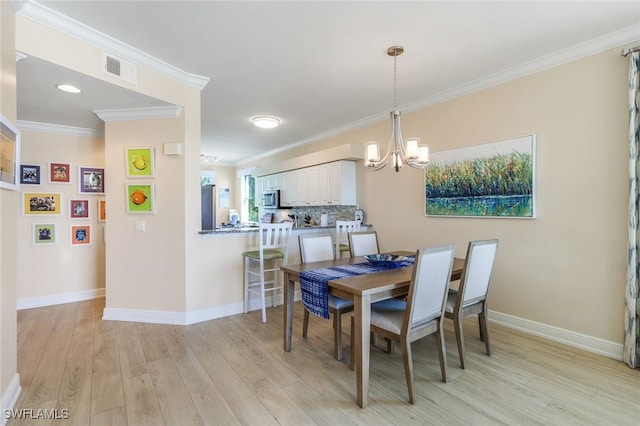 dining area with crown molding, a chandelier, and light hardwood / wood-style flooring