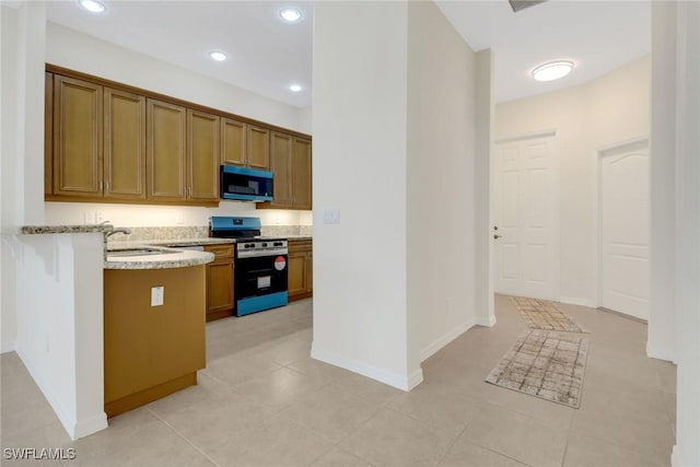 kitchen featuring sink, light stone counters, stainless steel range, light tile patterned flooring, and kitchen peninsula