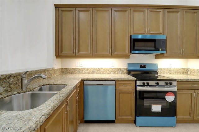 kitchen with sink, light tile patterned floors, light stone countertops, and appliances with stainless steel finishes