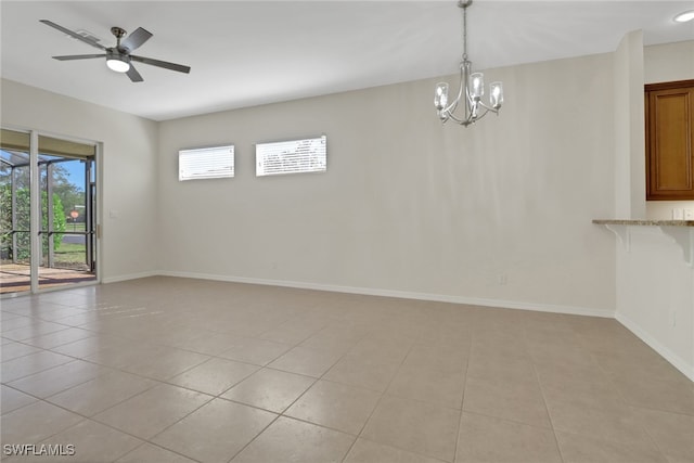 tiled empty room with ceiling fan with notable chandelier