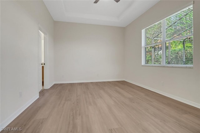 spare room featuring ceiling fan, a tray ceiling, and light hardwood / wood-style flooring