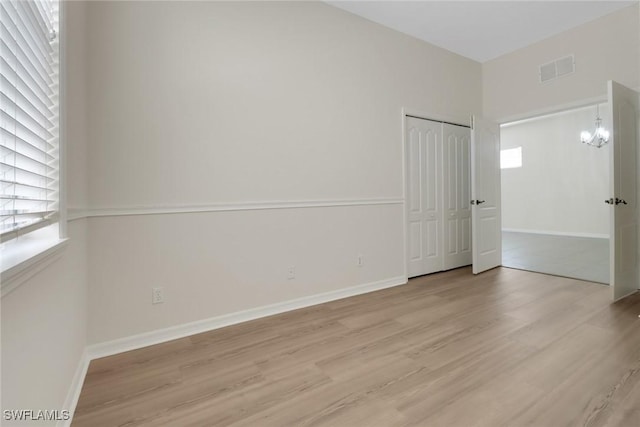 empty room featuring light hardwood / wood-style floors and a notable chandelier