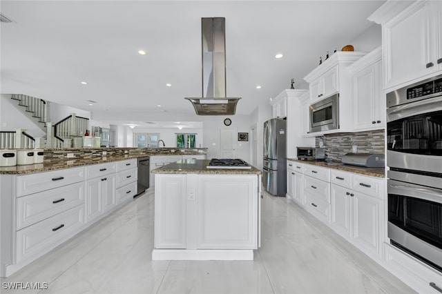 kitchen with tasteful backsplash, extractor fan, appliances with stainless steel finishes, a large island, and white cabinets