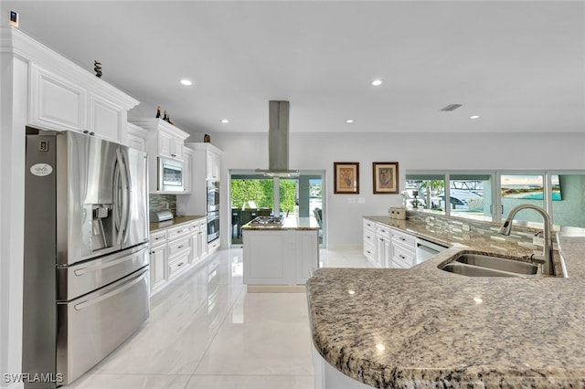 kitchen featuring visible vents, island exhaust hood, a large island with sink, a sink, and stainless steel appliances