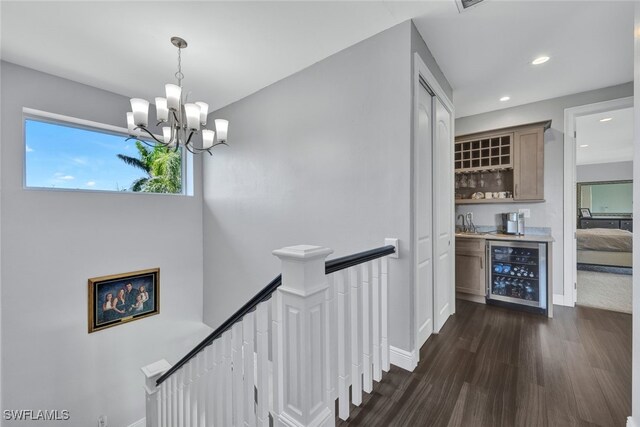 hallway with dark wood-style floors, baseboards, recessed lighting, wine cooler, and an upstairs landing