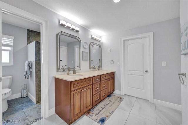 full bath featuring double vanity, toilet, baseboards, and a sink