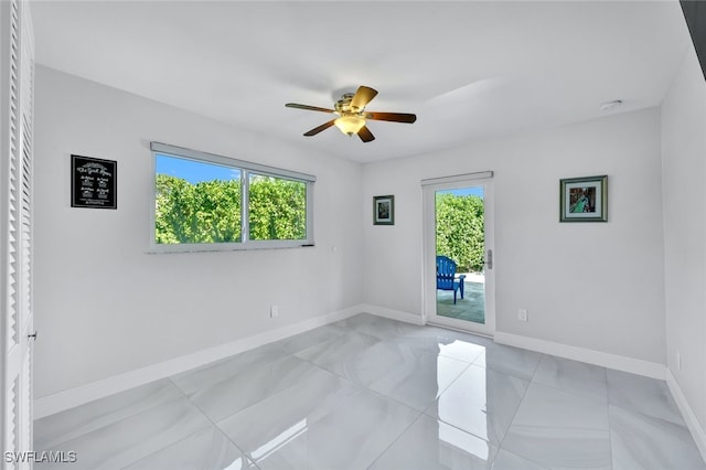 spare room with plenty of natural light, a ceiling fan, and baseboards