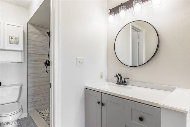 bathroom with tiled shower, vanity, and toilet