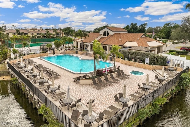 view of swimming pool with a patio, a water view, and a community hot tub