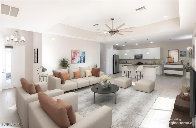 living room featuring ceiling fan with notable chandelier, sink, light tile patterned floors, and a tray ceiling